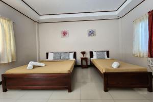two twin beds in a room with two windows at Dinah's Pension House in Puerto Princesa City