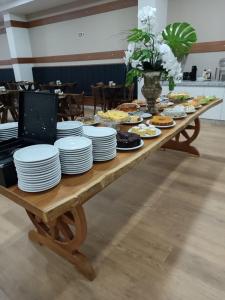 une table en bois avec des assiettes de nourriture dans l'établissement HOTEL MAESTRO EXECUTIVE PATO BRANCO, à Pato Branco
