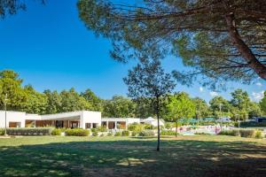 a tree in a park in front of a building at Easyatent Camping Stella Maris in Umag +18 photos
