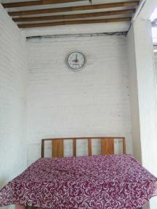 uma cama num quarto com um relógio na parede em Gubuk Baru Homestay em Tetebatu