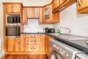a kitchen with wooden cabinets and a dishwasher at Flat 4, 2 Victoria Street in Armagh