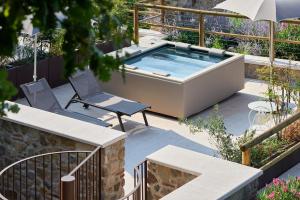 a hot tub in a garden with two chairs and an umbrella at Relais Rossar Boutique Hotel Garda & Hills in Costermano