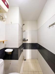 a bathroom with black and white tiles and a toilet at Campus Convenience at Scientia Apartment in Tangerang