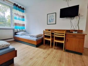 a room with two beds and a desk and a tv at Pokoje 24h ul. Bagrowa Kraków in Krakow