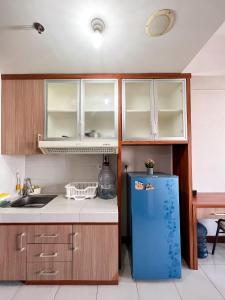 a kitchen with a blue refrigerator and wooden cabinets at Campus Convenience at Scientia Apartment in Tangerang