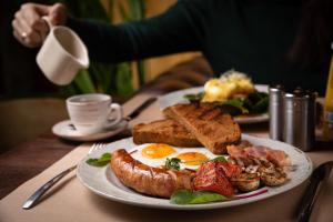 um prato de comida de pequeno-almoço com ovos, salsicha e torradas em voco Lythe Hill Hotel & Spa, an IHG Hotel em Haslemere