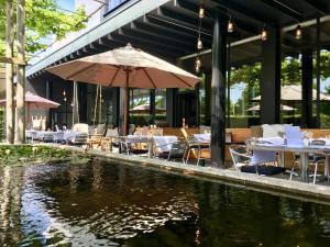 een restaurant met tafels en een parasol naast een vijver bij Serwir Hotel in Sint-Niklaas