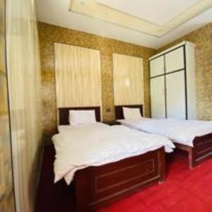 a bedroom with two beds with white sheets at Naqcho Paradise Inn Hotel in Skardu