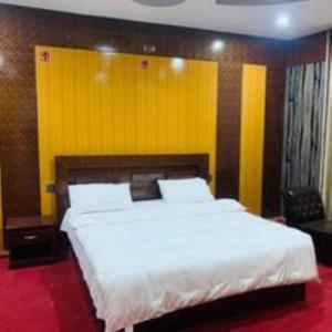 a bedroom with a large white bed with a yellow wall at Naqcho Paradise Inn Hotel in Skardu +6 photos