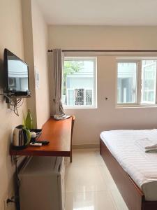 1 dormitorio con 1 cama y escritorio con TV en The Alley Saigon Hotel, en Ho Chi Minh