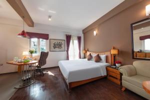 een hotelkamer met een bed, een bureau en een stoel bij Golden Sunshine Villa Hotel and Travel in Hanoi