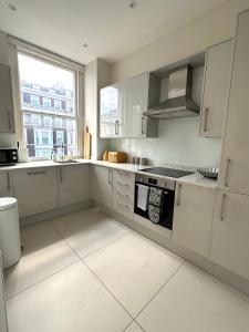 une cuisine blanche avec cuisinière et fenêtre dans l'établissement Cozy Flat in South Kensington, à Londres