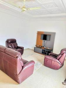 uma sala de estar com duas cadeiras de couro e uma televisão em Brufut Garden (TAF) Apartment em Brufut