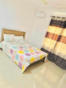 um quarto com uma cama com um edredão colorido em Brufut Garden (TAF) Apartment em Brufut