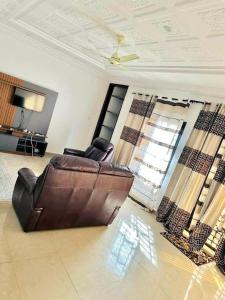 uma sala de estar com uma cadeira de couro e um sofá em Brufut Garden (TAF) Apartment em Brufut