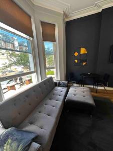 a living room with a sectional couch and two windows at Stylish studio for 3 near Regent’s Park n3 in London