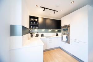 a kitchen with white counters and black cabinets at Bright & Quiet - Spacious Apt with Balcony & Lift in London