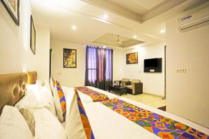 ニューデリーにあるHotel Olive New Delhiのベッドとリビングルームが備わるホテルルームです。