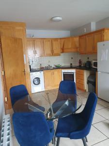 a kitchen with blue chairs and a glass table at Cosy beachfront apartment in Salthill Galway city in Galway