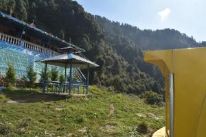 a building with a table and an umbrella on a hill at LaCliff Nature Home in Dhanaulti