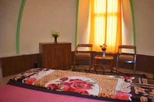 a bedroom with a bed and two chairs and a window at LaCliff Nature Home in Dhanaulti
