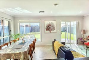 uma sala de jantar com mesa, cadeiras e janelas em Delightful 2-level home in Bardia em Ingleburn