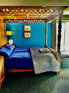 ein Schlafzimmer mit einem Himmelbett und einer blauen Wand in der Unterkunft Park Broom Lodges - Caldew House - Eden House - Petteril House in Carlisle