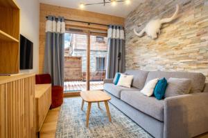 salon z szarą kanapą i ceglaną ścianą w obiekcie Echo du Pleney A001 w mieście Morzine