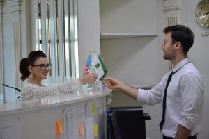 un hombre entregándole a una mujer un pedazo de papel en EmeraldGold en Bakú