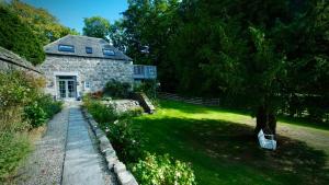 a stone house with a tree in the yard at The Lodges @ Barra Castle in Inverurie