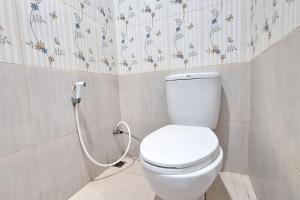 a white toilet in a bathroom with flowers on the wall at Hotel Jelita Mentawai Redpartner in Tua Pejat