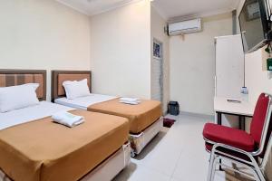 a room with two beds and a desk and a chair at Hotel Jelita Mentawai Redpartner in Tua Pejat