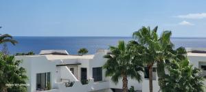una casa blanca con palmeras frente al océano en Bella Vista 414-Ocean Lanzamar- Puerto Del Carmen en Tías