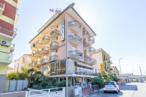 a building with a car parked in front of it at Hotel Naica in Rimini