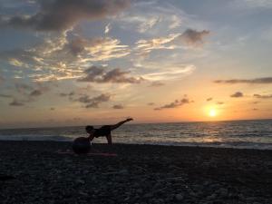 una persona haciendo una pose de yoga en la playa al atardecer en Jungle Aerial Arts Namaste Camp, 