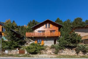 a log home with a deck on a mountain at Chalet Les Tilleuls - Jolie vue montagne et lac in Les Angles