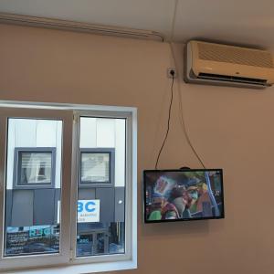 TV colgada en una pared junto a una ventana en Center Walk Studios en Bucarest