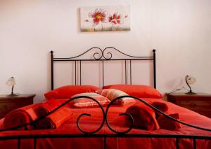 Cama roja con marco negro y almohadas rojas en Kamikos Casa Vacanze, SICULIANA, en Siculiana