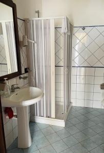 baño blanco con ducha y lavamanos en Kamikos Casa Vacanze, SICULIANA, en Siculiana