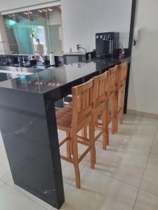 a black counter with a row of wooden chairs at Casa de temporada in Piumhi