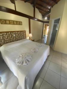 1 dormitorio con 1 cama grande con sábanas blancas en Pousada Bonns Ventos en Ilhabela