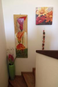 deux peintures sur un mur et un vase avec des fleurs dans l'établissement Bozikis House! A cosy apartment in the city centre, à Skiathos Chora