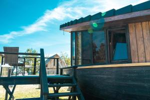 a small wooden cabin with a bench on a deck at Viesu nams Melnsils in Melnsils