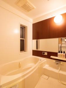 ein weißes Bad mit einer Badewanne und einem Fenster in der Unterkunft Muji Arashiyama Villa 無時嵐1階2階賃貸し 駅まで徒歩2分 in Kyoto