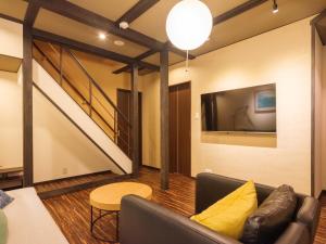 ein Wohnzimmer mit einem Sofa und einem TV in der Unterkunft Muji Arashiyama Villa 無時嵐1階2階賃貸し 駅まで徒歩2分 in Kyoto