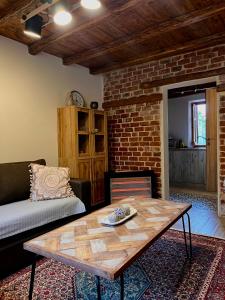 a living room with a table and a brick wall at Aristos Cottage in Káto Lekhónia