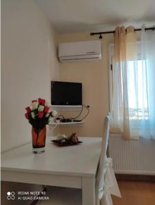 une table blanche avec un vase de fleurs sur elle dans l'établissement Bozikis House! A cosy apartment in the city centre, à Skiathos Chora