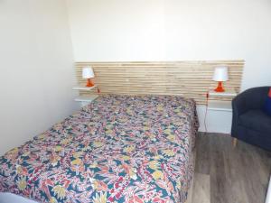 a bedroom with a bed and a blue chair and two lamps at Charmant T2 tout confort Cabourg in Cabourg