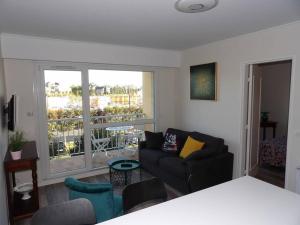 a living room with a couch and a large window at Charmant T2 tout confort Cabourg in Cabourg