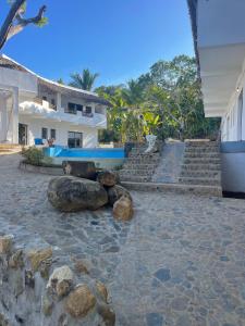 a house with rocks on the ground next to a building at Hotel Océan Beach Sakatia in Nosy Be